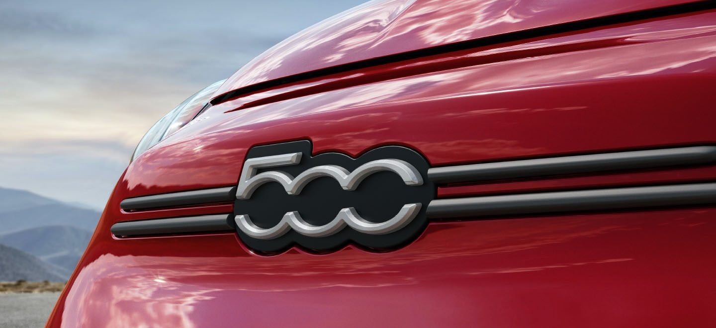 Primer plano del emblema 500 en la fascia delantera de un Fiat 500X Sport 2023 rojo.
