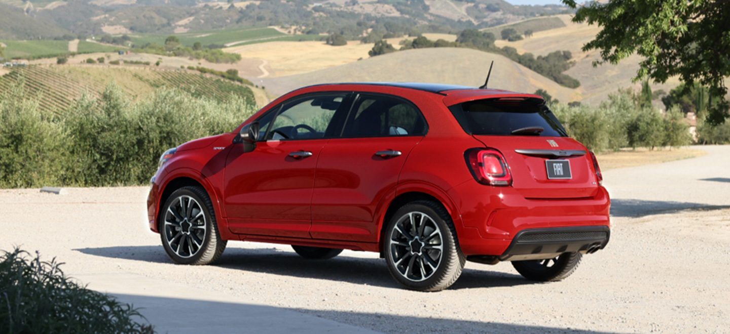 Display A three-quarter side view of a red 2022 Fiat 500X Sport with hills of vineyards in the background.