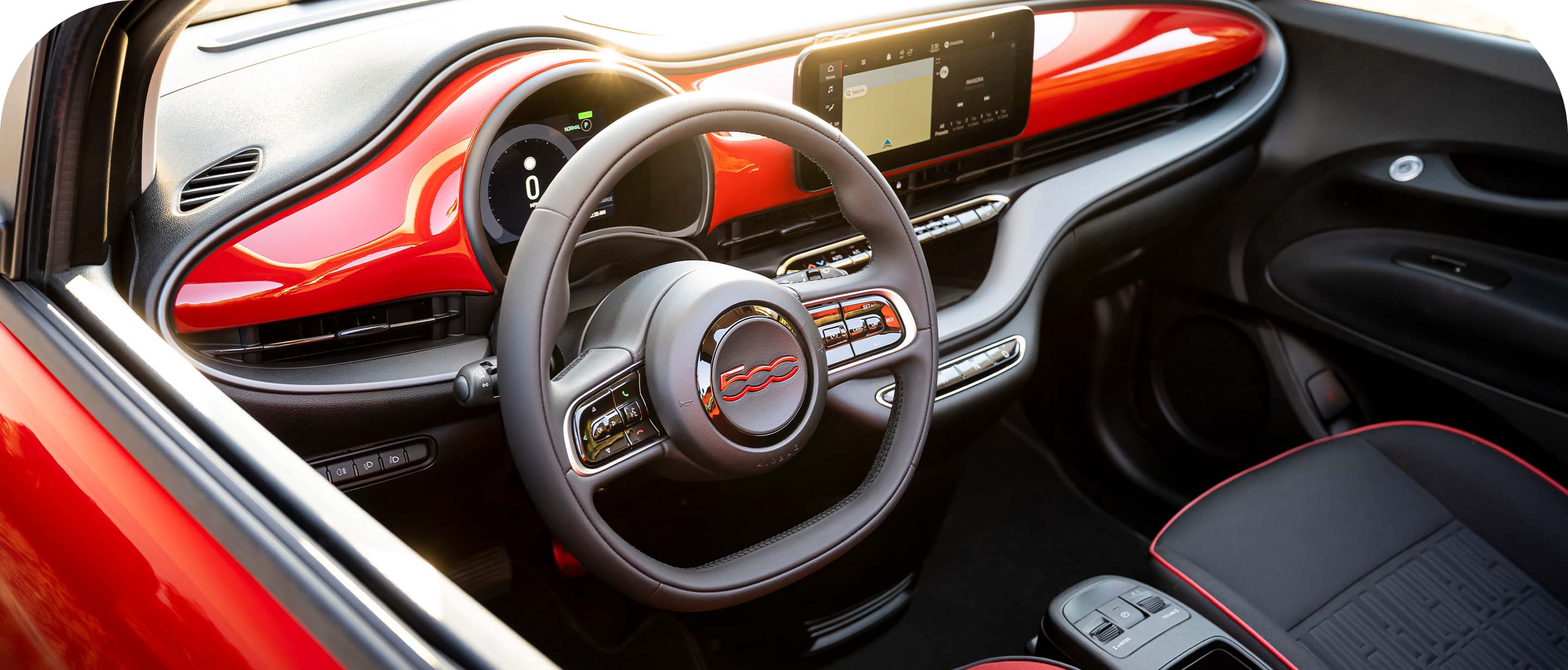 El interior del Fiat 500e Red 2024, con el foco puesto en el volante, la pantalla táctil de Uconnect y el tablero.